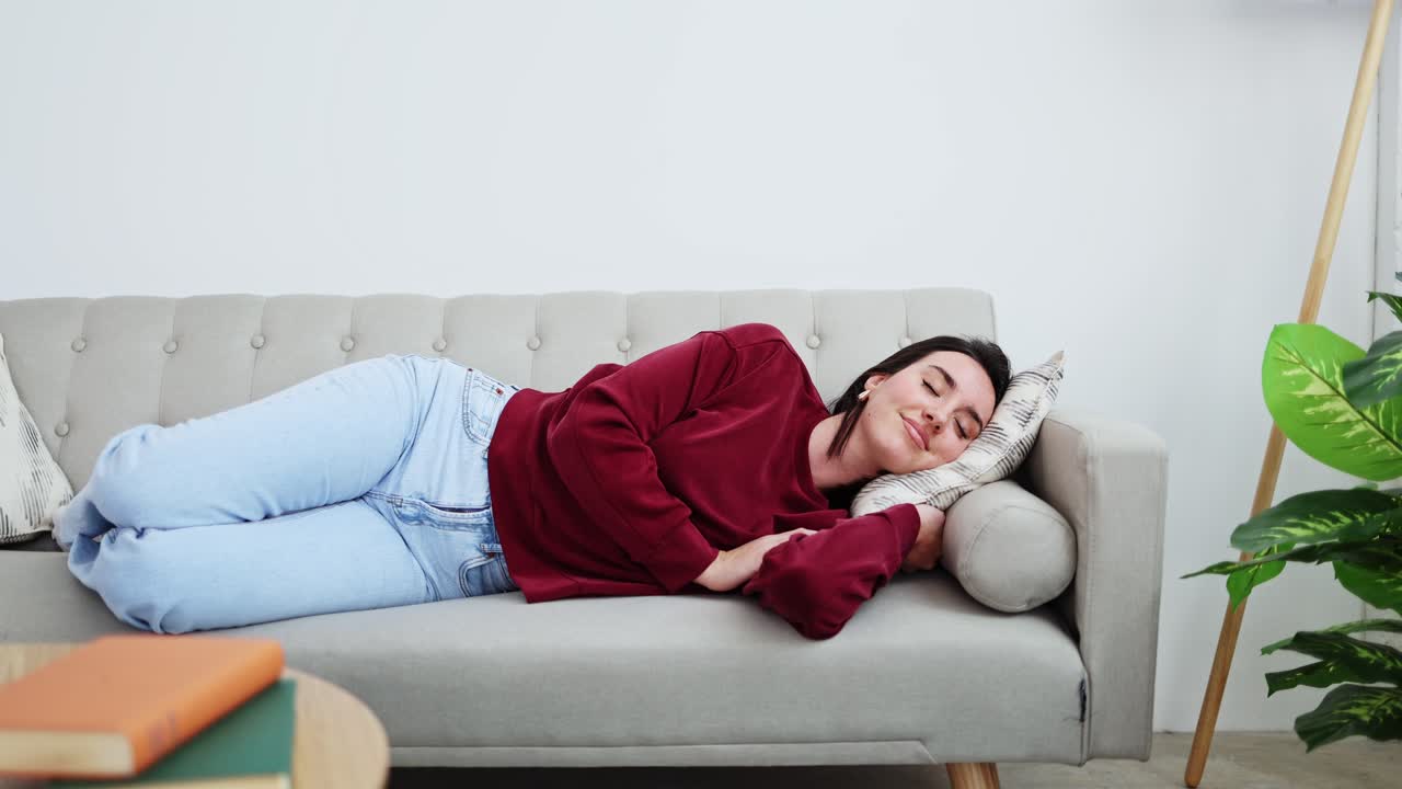 Giovane donna che si rilassa e si addormenta su un comodo divano a casa