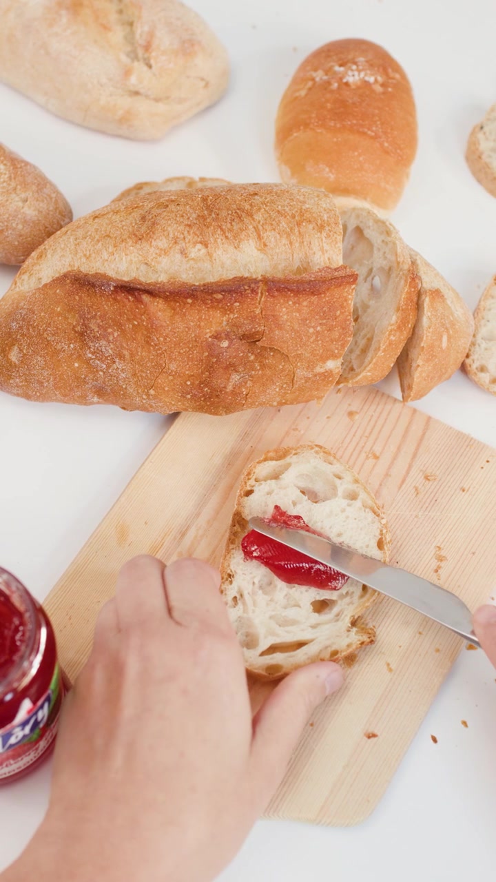 Spreading Strawberry Jam on a Slice of Fresh Bread