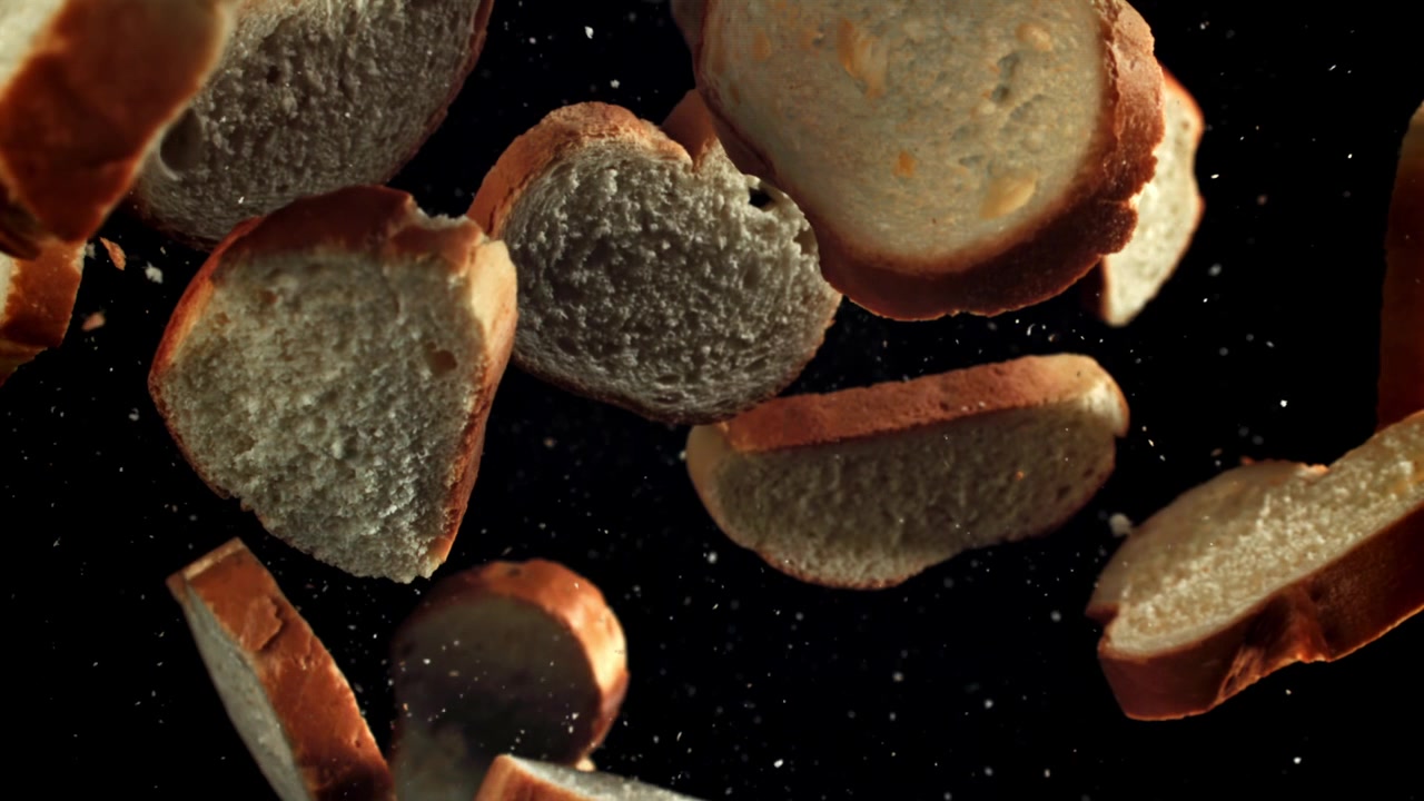 Friske brødskiver, der falder i slowmotion på sort baggrund