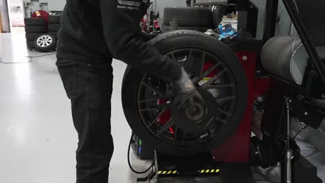 Tire-workshop-technician-setting-up-the-wheel-for-auto-balancing