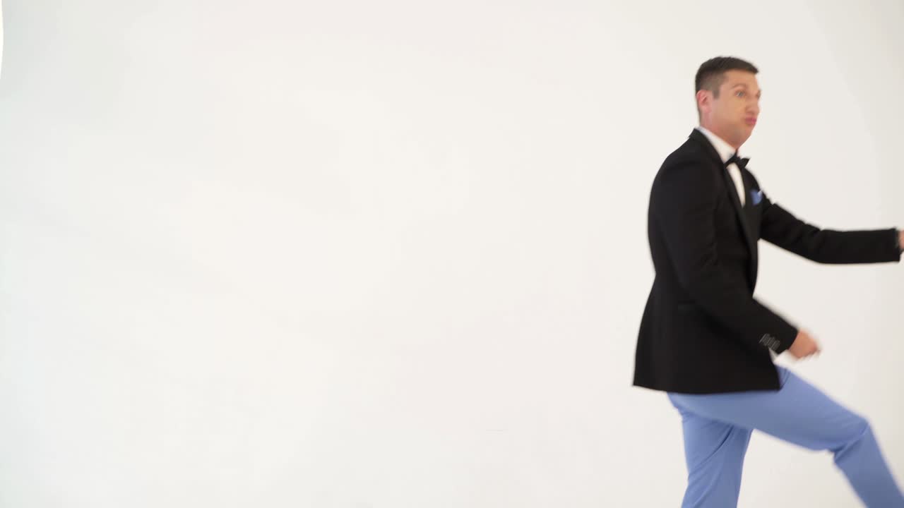 cheerful man in light-colored pants and black jacket is parodying a guitarist which playing at concert on a white background in the studio