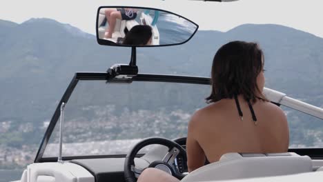 young lady holding the boat wheel while turning around with motorboat