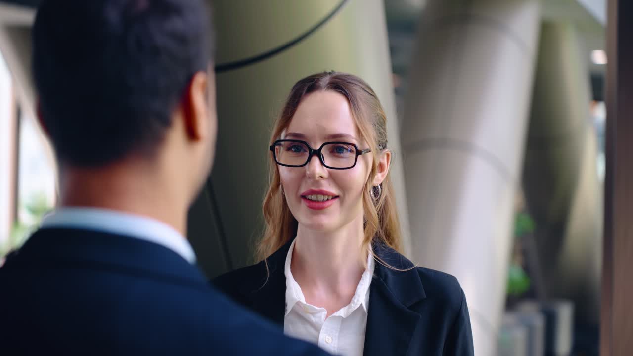 Close up face of beautiful businesswoman smiling happily while flirting with male colleague during a break in a modern corporate office hallway illustrating office relationship concept