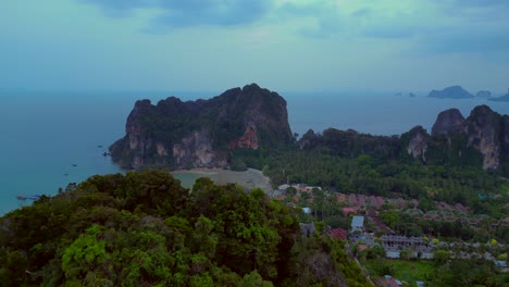 limestone cliffs and lush tropical jungle of railay beach, krabi, thailand, at dusk, creating a dramatic and serene landscape. best aerial view flight overflight flyover drone