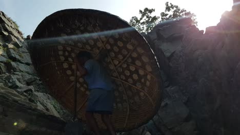 a man carrying a coracle on one hand and paddle on the other hand while climbing steps in in hogenakkal, tamilnadu, india