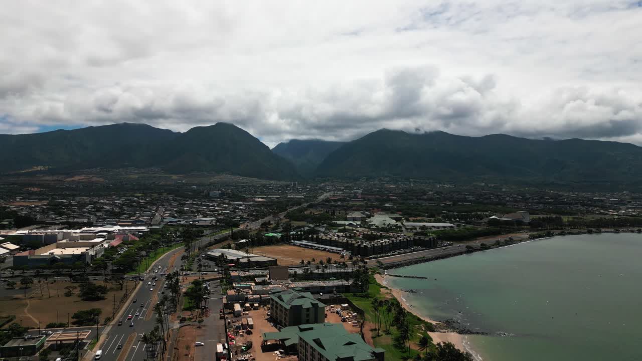 Aerial View of a Coastal City with Mountains and Cloudy Sky