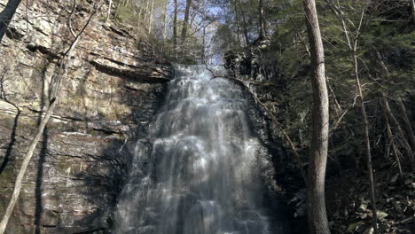 panning down to large cascading waterfall in peaceful appalachian forest, 4k