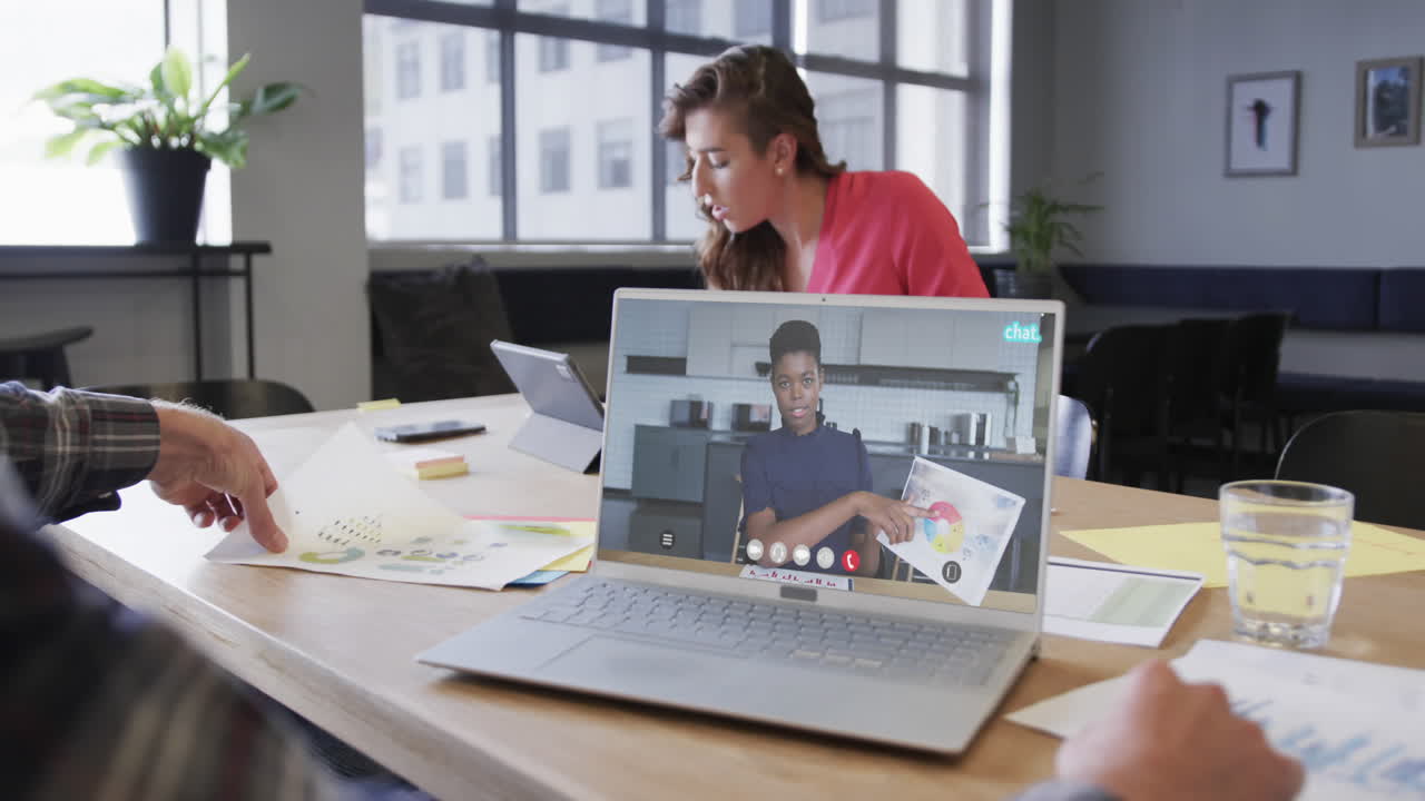 hombre de negocios caucásico en una llamada de video portátil con una colega afroamericana en la pantalla