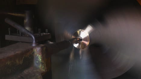 an old machine drills a hole in a metal rod, showcasing precision engineering and industrial production