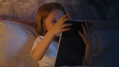 Girl-does-winner-gesture-and-presses-key-on-tablet-in-bed