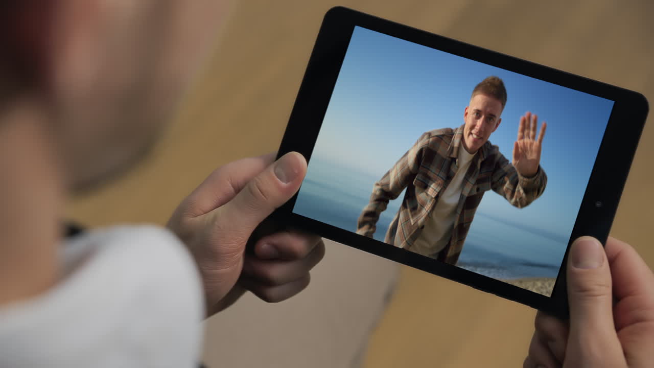 Primo piano di un uomo rilassato che fa una videochiamata a un amico da casa. Un viaggiatore che parla online tramite tablet