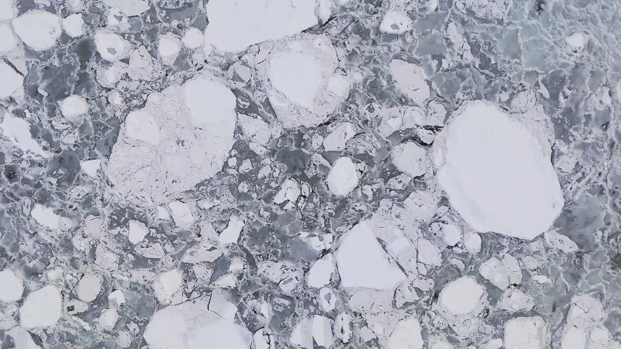 Brash ice completely covering the surface in overcast lighting, top down drone zoom out shot