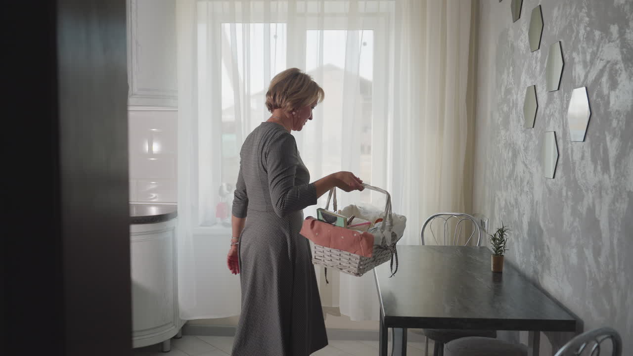 Back view of woman entering bright modern kitchen dropping shopping basket on dark table near window with sheer curtains cozy home interior stylish wall decor daily routine