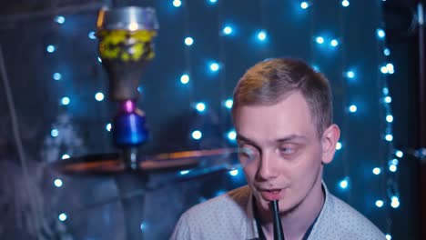 hombre fumando narguile en un club nocturno