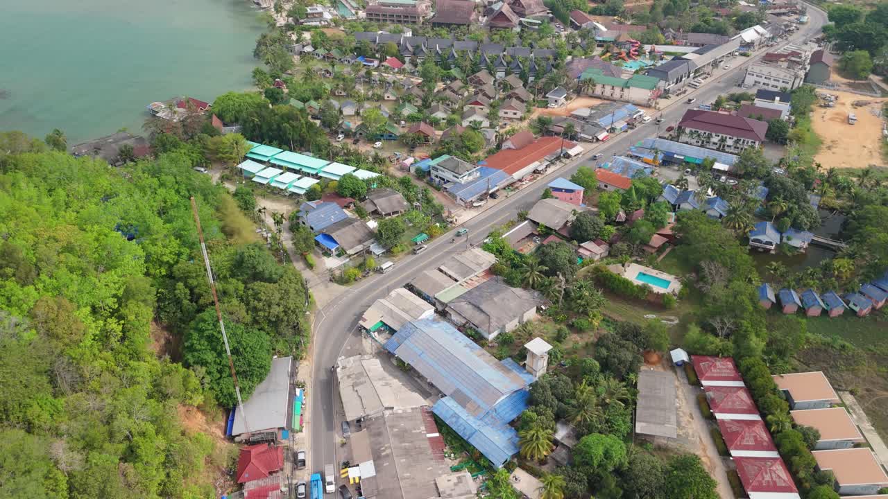 aerial drone tilt footage of Klong Prao village on Koh Chang with main road, shops, mountains and ocean in Thailand