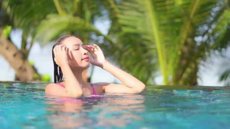 Close-up-of-a-sexy-woman-in-a-swimming-pool-pushing-her-wet-hair-from-her-face