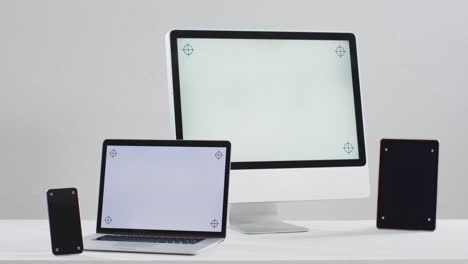 video of laptop, smartphone, tablet and computer on white table with copy space in office