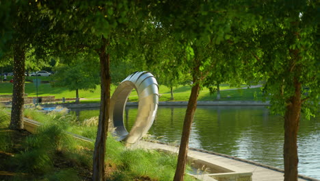 La-Vista-Del-Monumento-De-Los-Sentidos-Místicos,-Banco-De-Arte-A-Través-De-La-Línea-De-árboles,-Domina-El-Canal-Del-Bosque-En-Un-Día-Soleado.