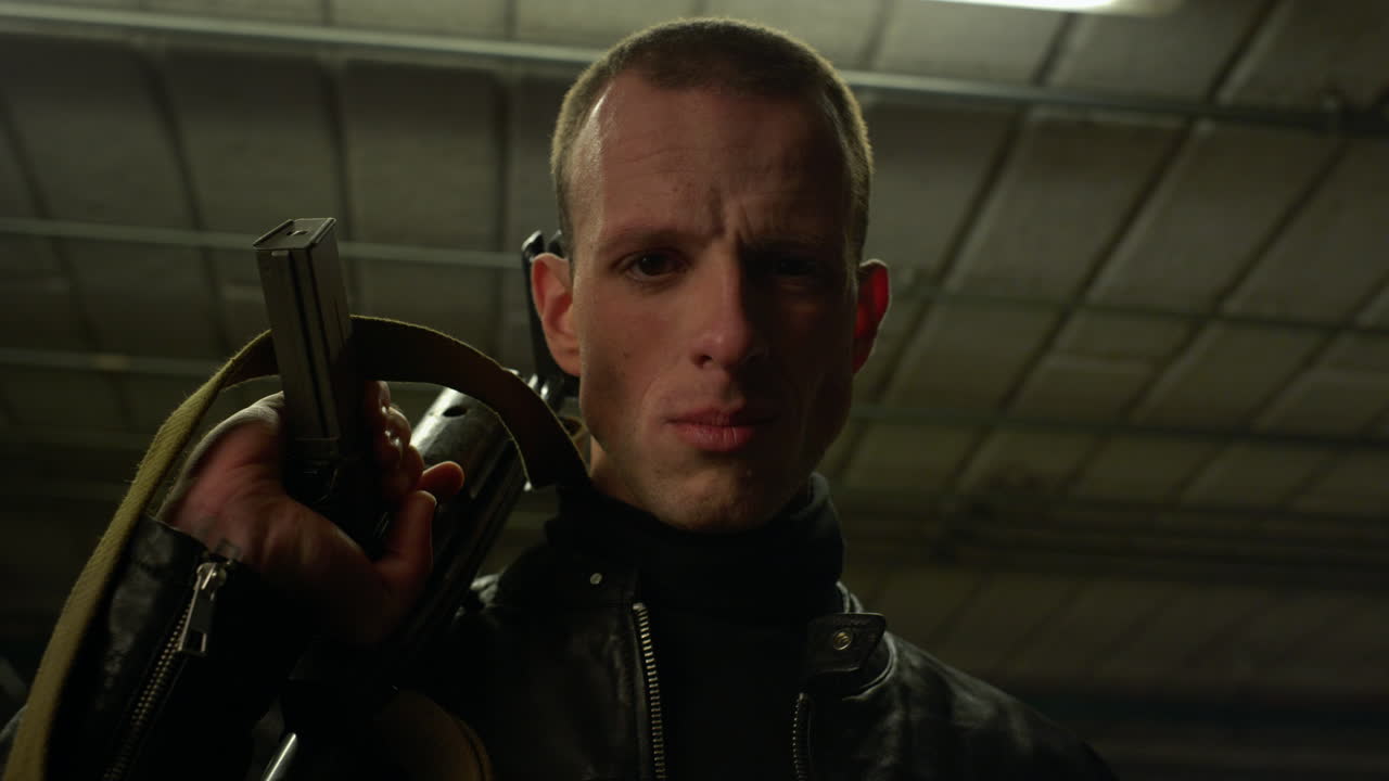 Man with sniping rifle looking at camera. Male criminal holding weapon