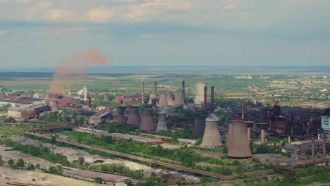 Old-industrial-complex-showing-multiple-tall-smokestacks-on-a-sunny-clear-day,-tracking-shot