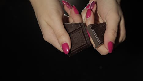 la mujer rompe una barra de chocolate negro. primer plano. cámara lenta.