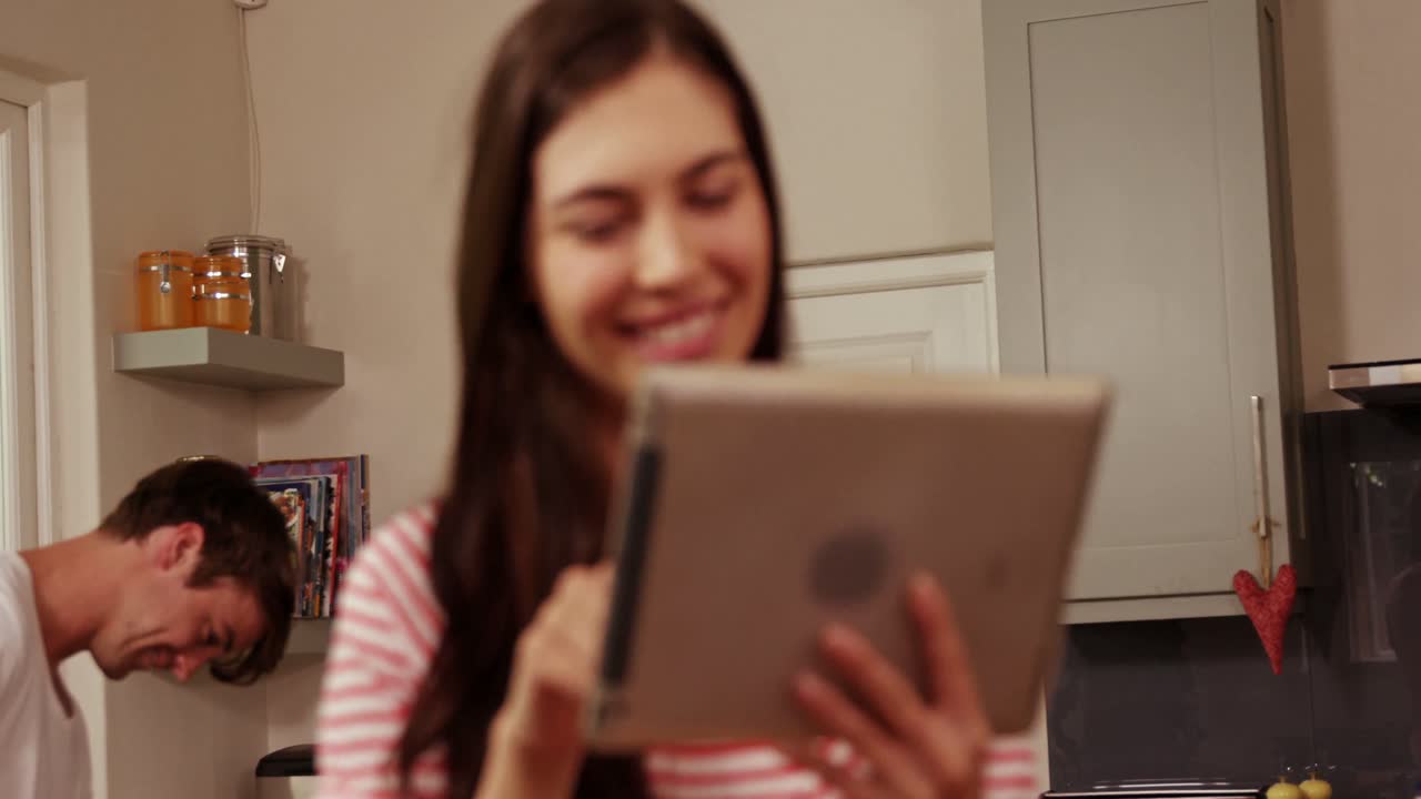pareja sonriente planchando y usando la tableta