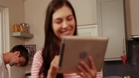 pareja sonriente planchando y usando la tableta