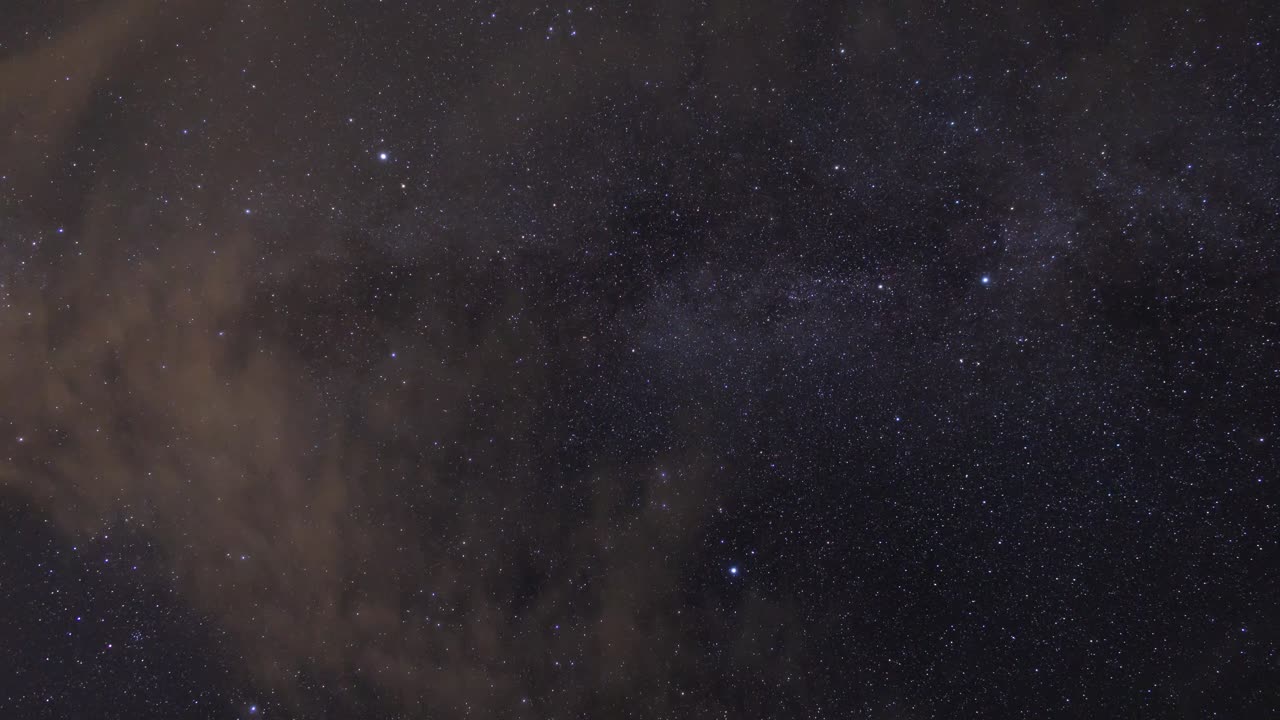 Milky Way stars visible through scattered clouds in dark night sky above England, capturing celestial beauty, faint star clusters, and atmospheric cosmic scene with soft cloud cover