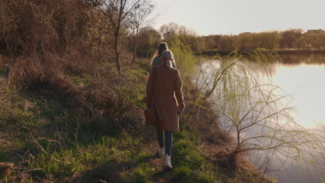 women walking along a lakeside path at sunset