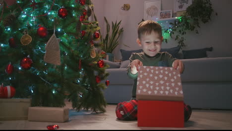 Happy-Smiling-Little-Boy-Opens-His-Christmas-Gift-From-Santa-Claus.-boy-opening-Christmas-gift-at-home.-High-quality-4k-footage