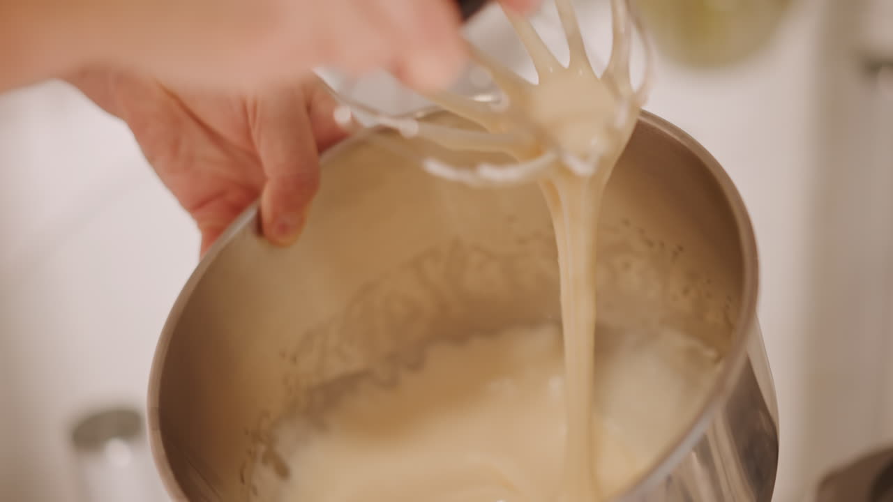 Mescolare l'impasto della torta di zucca in una ciotola, fornaia casalinga che mescola una crema liscia con una frusta a mano, versare la panna e osservare la formazione di una consistenza setosa nella ciotola di acciaio inossidabile, calda atmosfera in cucina, spezie autunnali, accogliente.