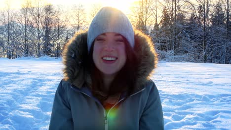 happy woman blowing snow in snowy forest