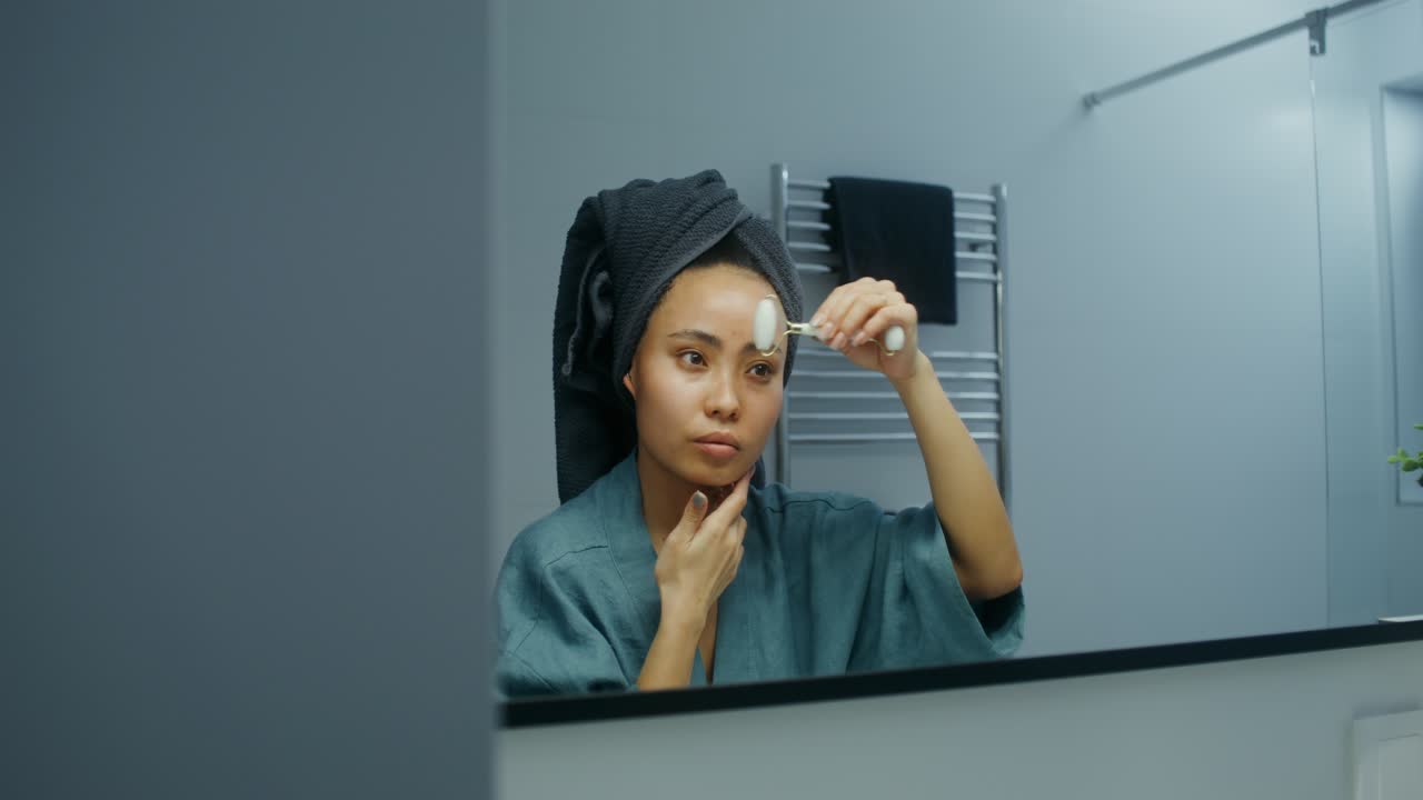Donna che usa un rullo facciale in bagno