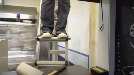 dolly in to worker on ladder in restaurant during renovations