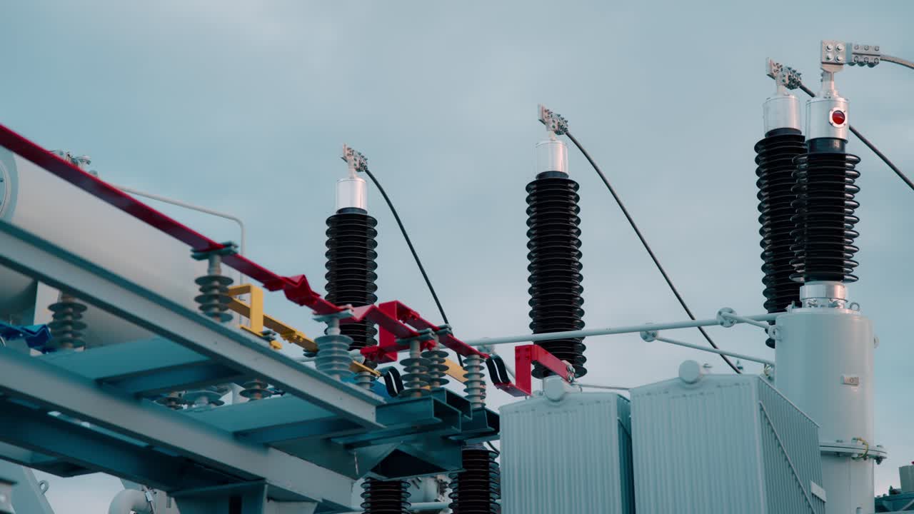 Electrical transformers at a power station, cloudy sky backdrop