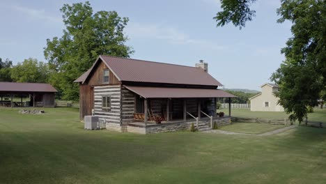 4k aerial pushing in on small quaint historic log cabin in rural scenery