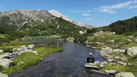 Frau-Sitzt-Auf-Einem-Felsen-Am-Fluss-Im-Nationalpark-Piringebirge,-Bulgarien