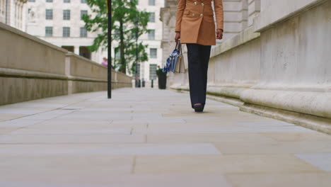 close up of businesswomen's legs and feet wearing modern business suits walking to work past city office buildings