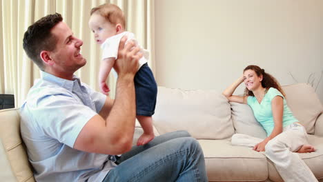 Mother-watching-her-partner-play-with-their-baby-on-the-couch