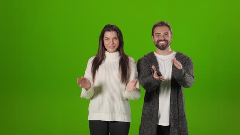 man and woman clapping in hands over green background