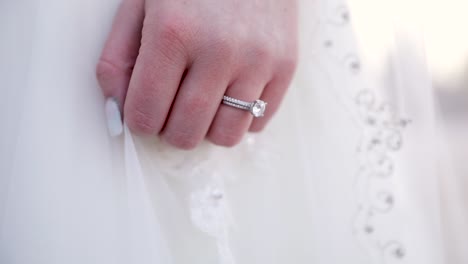 diamond wedding ring on hand of bride in white dress