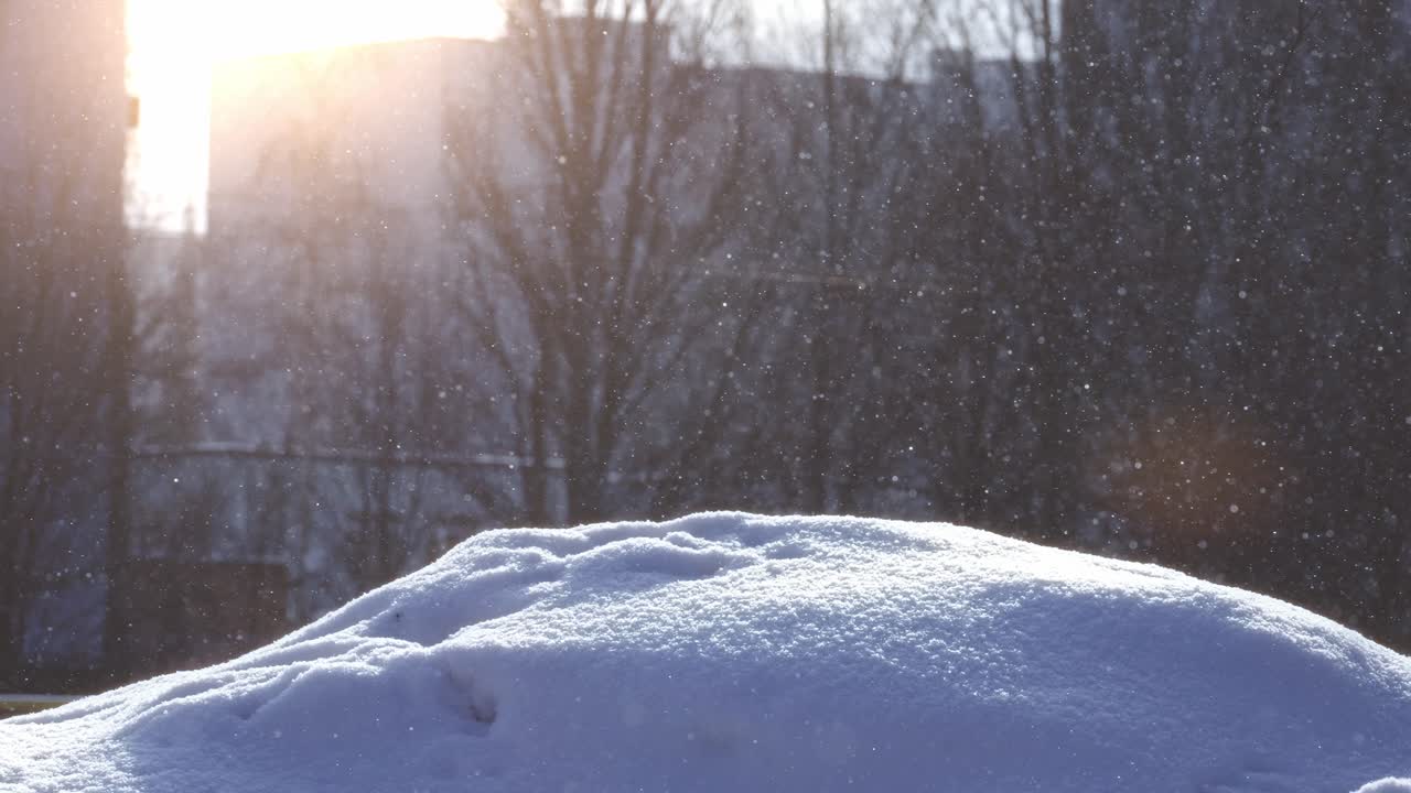 冬の陽光にきらめく雪の結晶が、新雪の吹きだまりに舞い落ちる様子