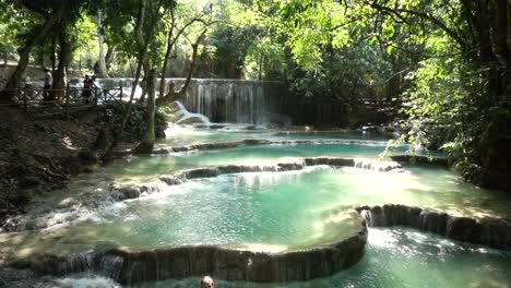 slowmotion wideshot of kuang si waterfall with tourists watching