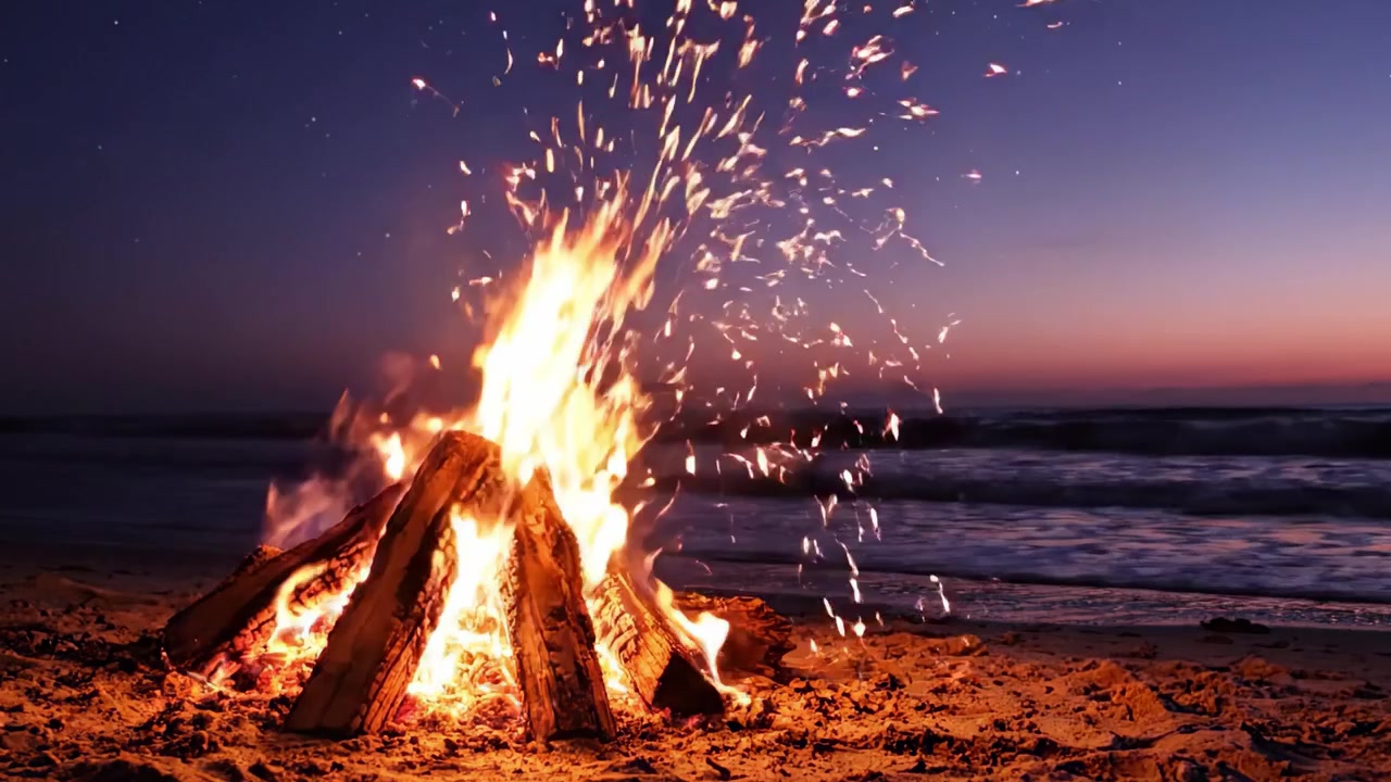 Un tranquillo falò sulla spiaggia illumina il cielo crepuscolare, creando un caldo bagliore contro la luce che svanisce dell'orizzonte oceanico e la notte stellata.