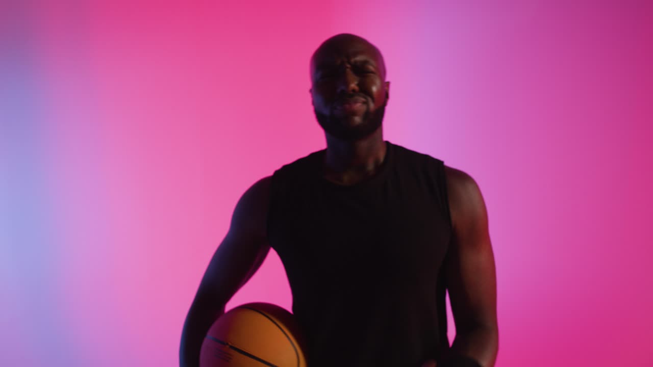 남성 농구 선수 의 클로즈업 스튜디오 초상화 는 분홍색 으로 조명 된 배경 에 대해 공 을 드리블 하고 뛰고 있다 4