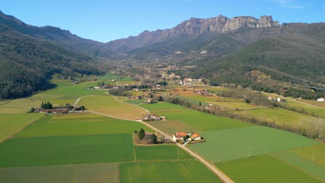 cultivated valley with animal farms seen from the air with a drone and in the background the silhouettes of the mountain on a sunny day