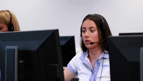 Casual-young-woman-with-headset-using-computer