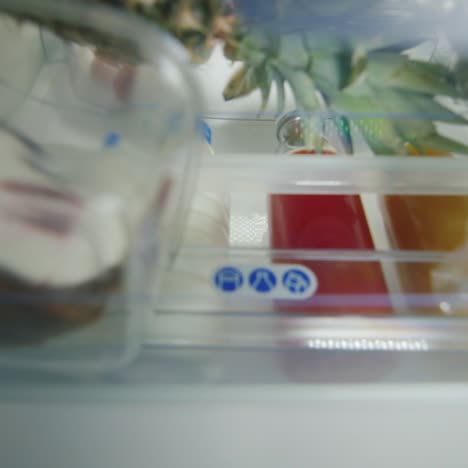 joven toma un pastel del refrigerador y habla por teléfono