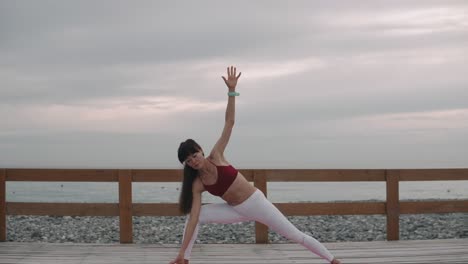 woman practicing triangle pose yoga at the beach