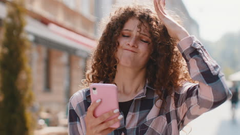 surprised young woman use smartphone loses bad news fortune loss fail outdoors in city street